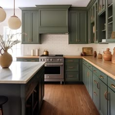 a kitchen with green cabinets and wood flooring is pictured in this image, there are vases on the counter