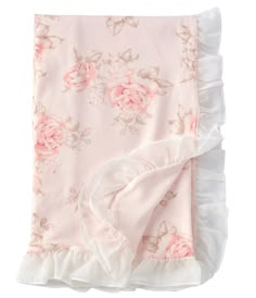 a pink blanket with white ruffles and roses on the bottom is laying down