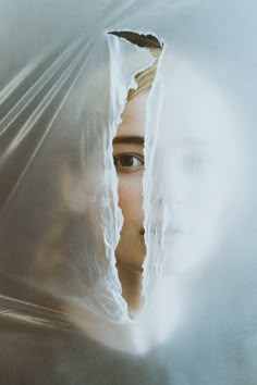 a woman's face is seen through the plastic covering her head and neck as she stares into the camera