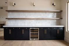 an empty kitchen with black cabinets and white counter tops