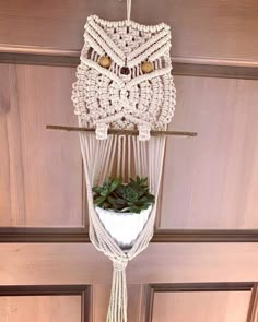 an owl hanging from the ceiling with a plant in it