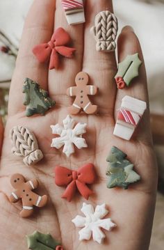 a person's hand is full of miniature christmas decorations and cookies on it,