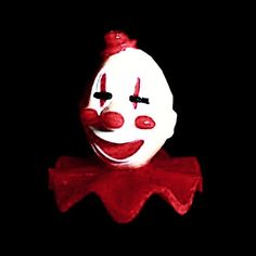 a white and red clown mask with black background