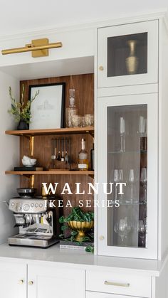 a kitchen with white cabinets and shelves filled with wine glasses, coffee maker and other items