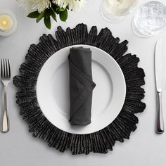 a white plate topped with a black napkin next to silver utensils and flowers