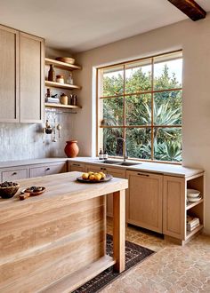 a kitchen with wooden cabinets and an island in front of a window that looks out onto the trees