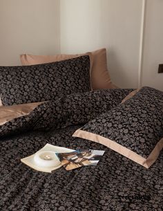 a bed with black and tan sheets, pillows and pictures on the pillowcases