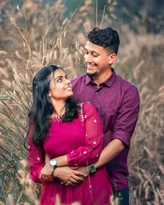 a man and woman standing next to each other in tall grass