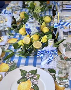 the table is set with lemons and blue and white plates, silverware, and flowers