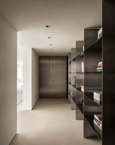 an empty room with bookshelves and shelves in the center, leading to another room