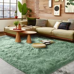 a living room filled with lots of furniture and green rugs on top of a wooden floor