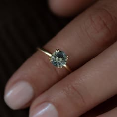 a woman's hand with a ring on it and a blue diamond in the middle