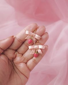 a person holding two small bows in their hand, one with a cherry on it