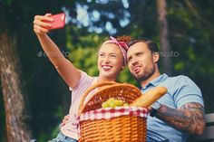 a man and woman sitting on a bench taking a selfie with their cell phone