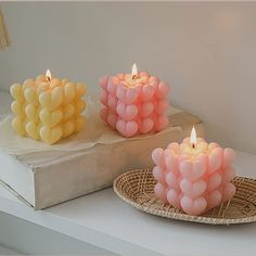 three candles sitting on top of a white table next to a book and lamp shade