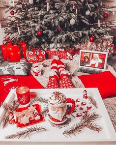 a christmas tree is decorated with red and white plaid stockings, coffee mugs, candles, and other holiday decorations