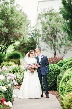 a bride and groom standing in front of some bushes