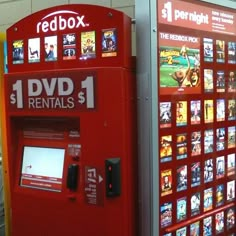 a red box vending machine in front of a wall with movies on the display