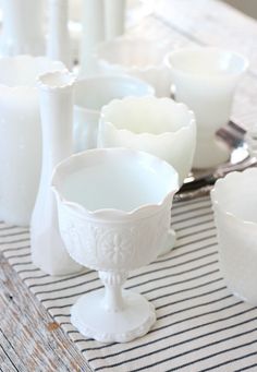 a table topped with white dishes and candles