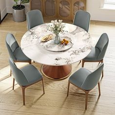 a dining room table with blue chairs around it and a white marble topped centerpiece