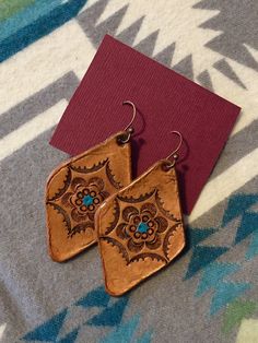 two pairs of earrings sitting on top of a table next to a red piece of paper