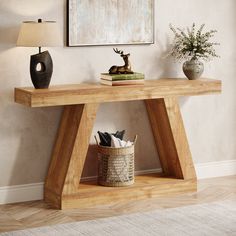 a wooden table with a basket and lamp on it in front of a white wall