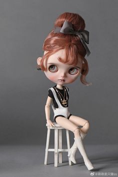 a doll sitting on top of a stool with a bow in it's hair