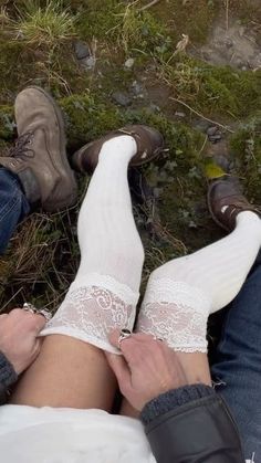 two people sitting on the ground with their feet up and one person wearing white socks