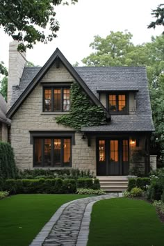 a house with stone steps leading to the front door and windows, surrounded by greenery