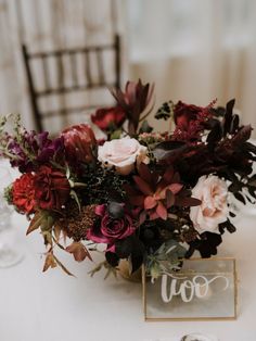 a vase filled with flowers sitting on top of a table next to a wooden sign