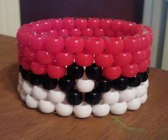 a close up of a bracelet on a table with red, white and black beads