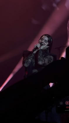 a man with tattoos on his arm singing into a microphone in front of a crowd