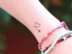 a close up of a person's wrist with a heart tattoo on the wrist