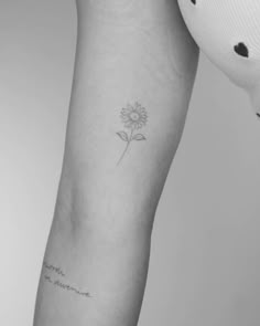 a woman's arm with a small flower tattoo on the left side of her arm