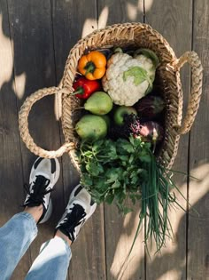 a person standing in front of a basket filled with fruit and vegtables