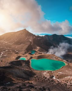 green lakes surrounded by mountains under a cloudy sky