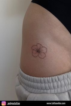 a woman's stomach with a small flower tattoo on the side of her belly