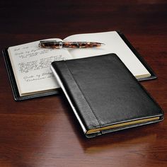 an open notebook and pen sitting on top of a wooden table