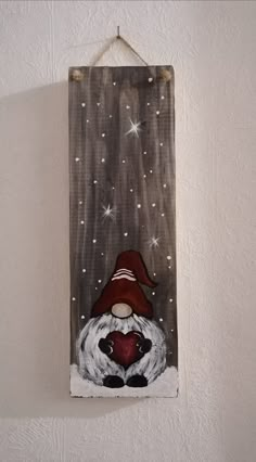 a wooden sign hanging on the wall with a gnome holding a heart in his hands