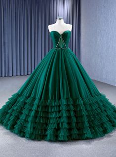 Quintessentially captivating, this prom dress features a sculpted bodice that artfully frames the decolletage, drawing attention to the delicate yet determined lines of the heart-shaped neckline. The rich emerald green velvet hugs the figure before exploding into a sea of structured tulle ruffles, creating a breathtaking ballgown silhouette that promises to leave a lasting impression. As regal as it is refreshing, this gown is a celebration of classical beauty with a modern twist. Each ruffled layer adds a touch of whimsy to the grandeur, inviting a sense of playful sophistication to an evening of elegance. Perfect for a night where every detail counts, this dress is an unforgettable emblem of style. Barbie Gowns Princesses, Emerald Green Lace Dress, Emerald Green Lace, Green Ball Gown, Green Lace Dress, Classical Beauty, Tulle Ruffles, Hand Style, Emerald Green Velvet