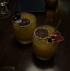 two glasses filled with drinks sitting on top of a wooden table