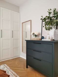 a dresser with two vases on top of it and a plant in the middle