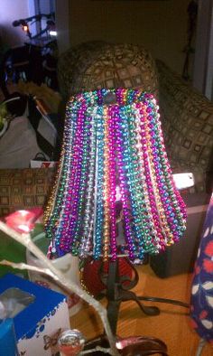 a lamp that has been decorated with beads and lightshade on the table next to it