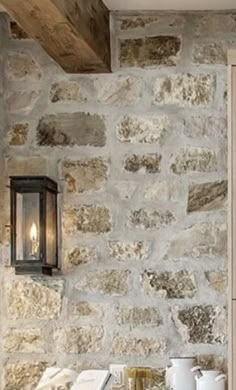 a stone wall with a lantern hanging from it's side and two cups on the table