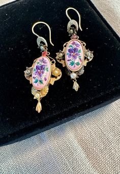 Victorian Earrings dangles tests for 10 & 14K gold, oval lovely enameled violets center with floral gold setting jeweled with genuine pearls and I believe a prong set Tourmaline.  Condition is very good for their age any slight wear commensurate with age, pictures show the details.  Length approx.- 1 7/8", wt for pair 4.8 grams.  True to the Victorian era love for nature-this aesthetic earring design is a splendid example.  Delicate and captivating. Elegant Oval Enamel Jewelry, Vintage Pierced Enamel Jewelry, Victorian Style Pink Earrings For Gift, Antique Enamel Earrings For Gift, Antique Enamel Earrings As Gift, Pink Victorian Earrings For Gift, Vintage Enamel Wedding Earrings, Vintage Pierced Enamel Earrings, Antique Pink Earrings Gift