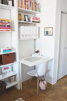 a white desk sitting in the corner of a room next to a bookshelf