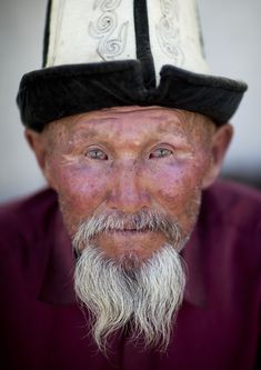 an old man with a white beard wearing a black and white hat on top of his head