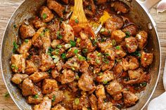 a pan filled with meat and vegetables on top of a wooden table