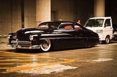 an old black car parked next to a white truck