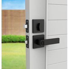 an open door with black handles and knobs on the side of it, in front of a green yard